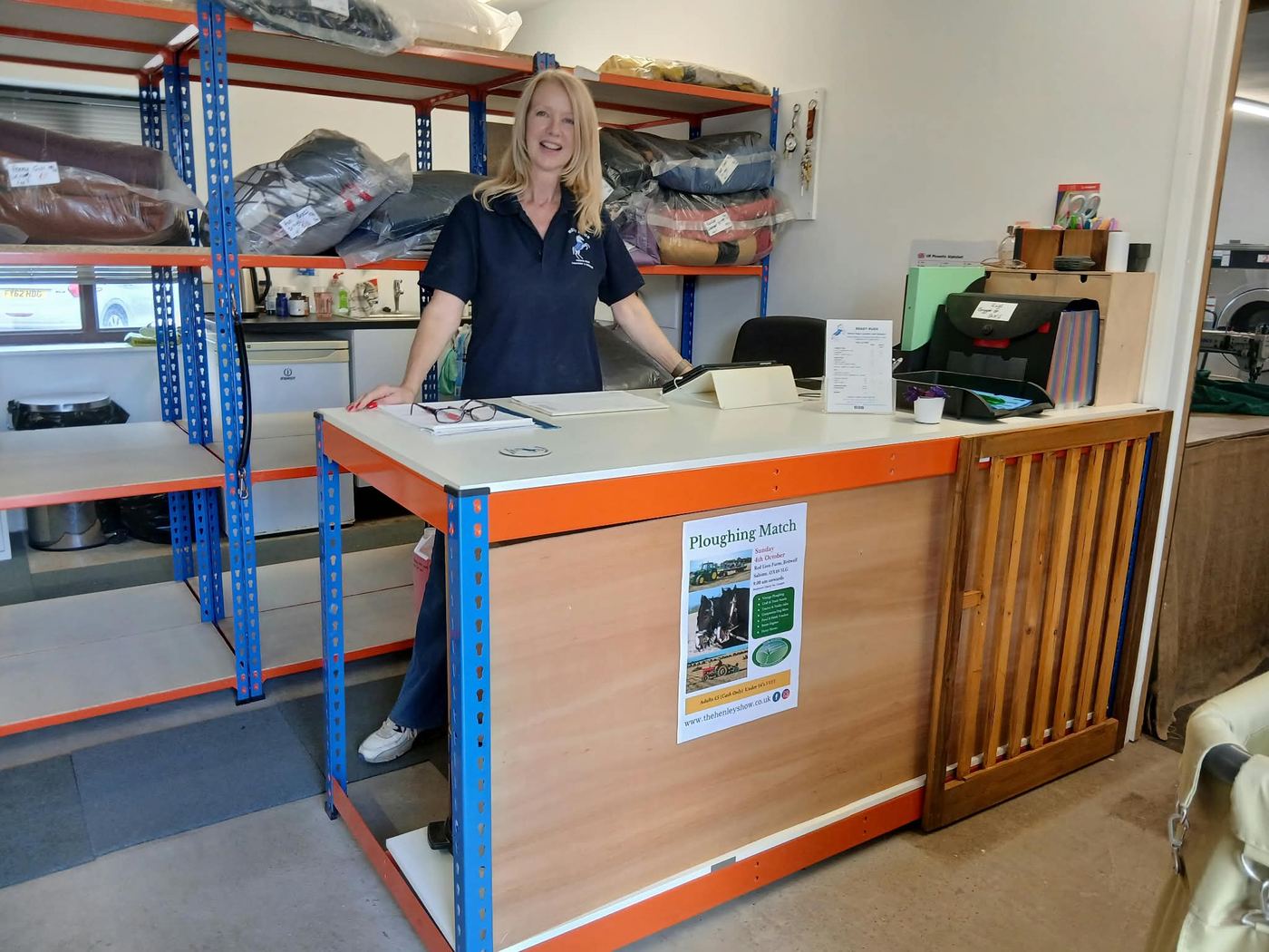 Kathy at the Ready Rugs reception counter, with shelves of washed rugs behind her
