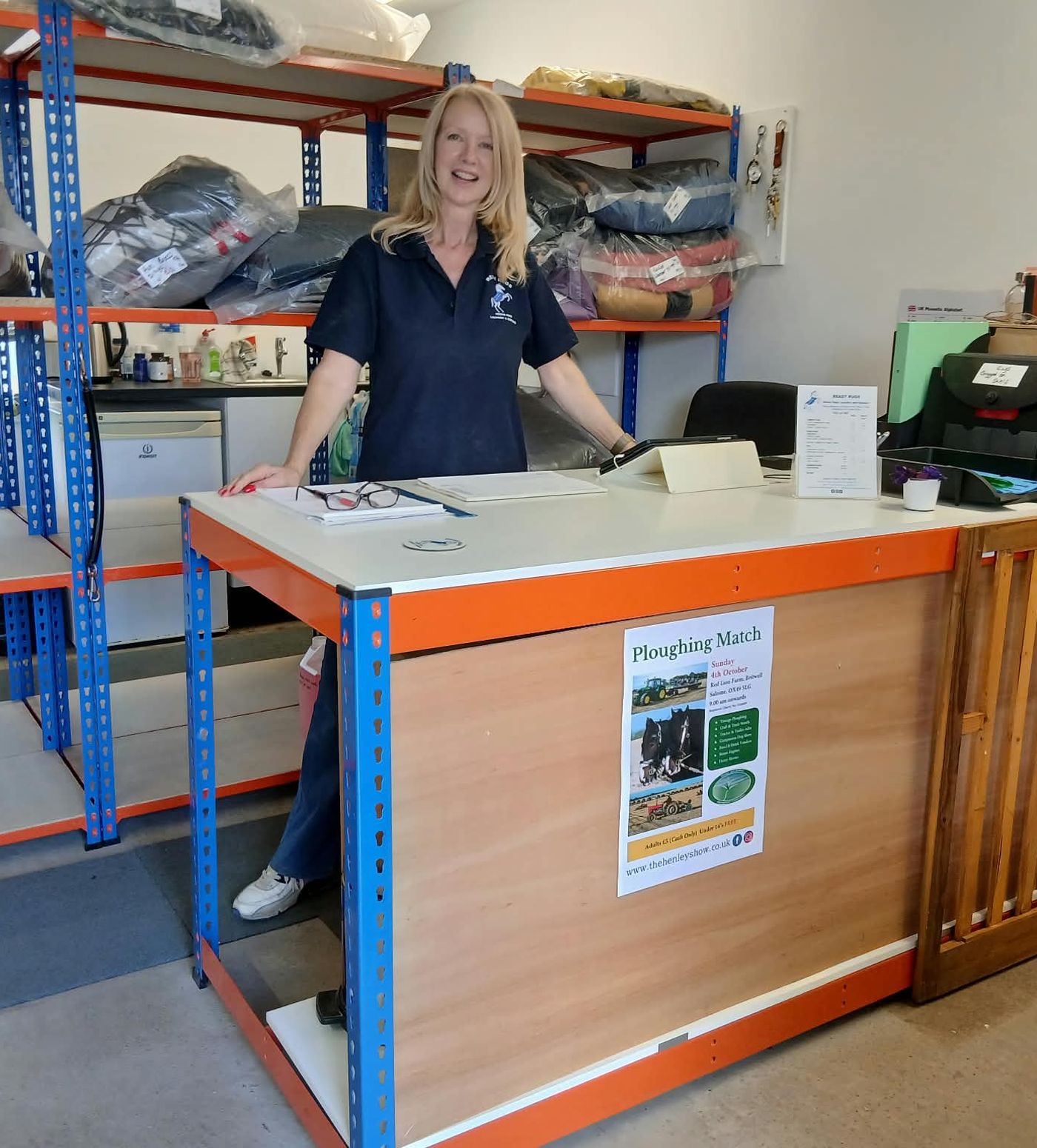 Kathy at the Ready Rugs reception counter, with shelves of washed rugs behind her