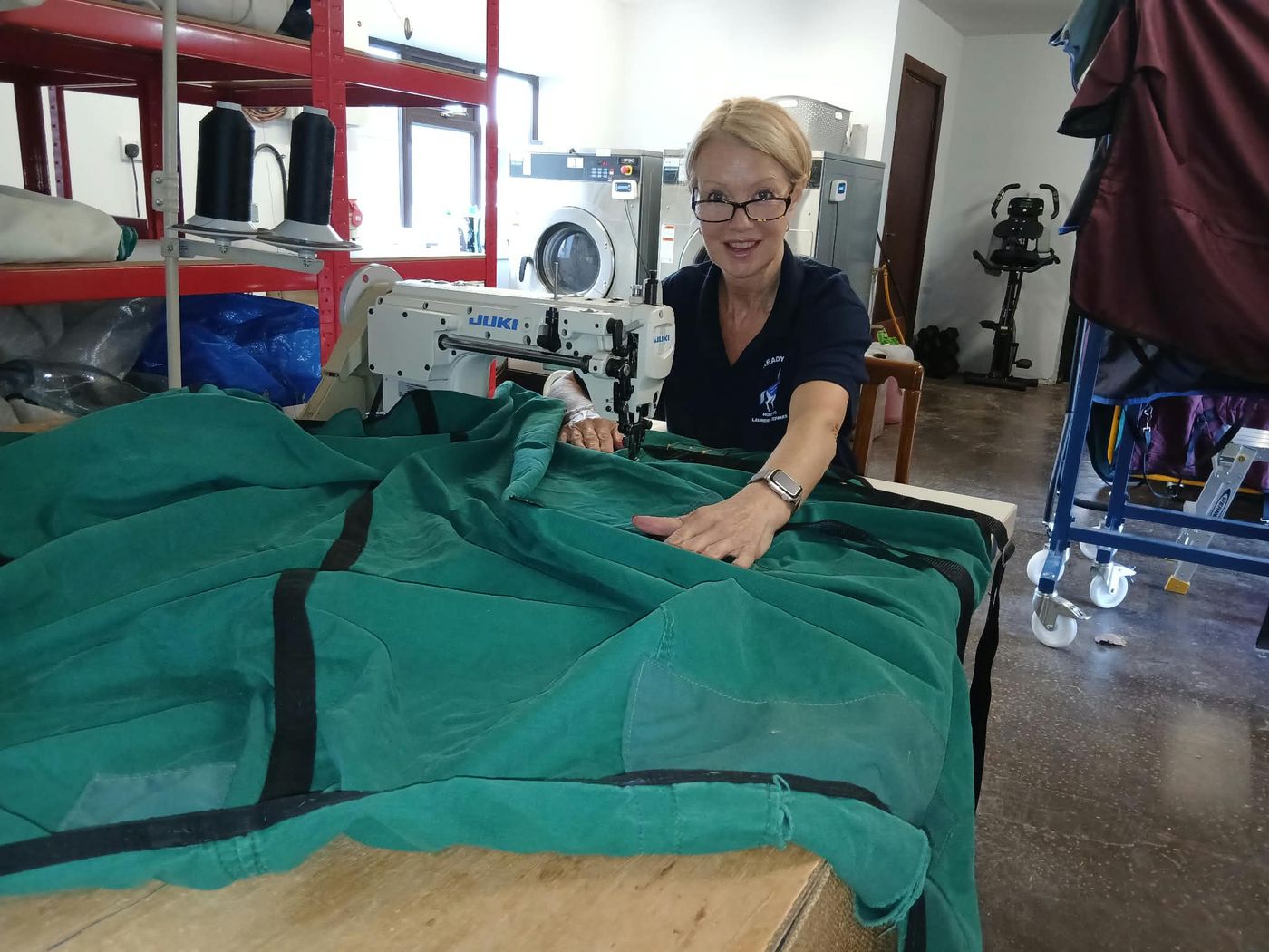 Kathy repairing a green horse rug at her sewing machine