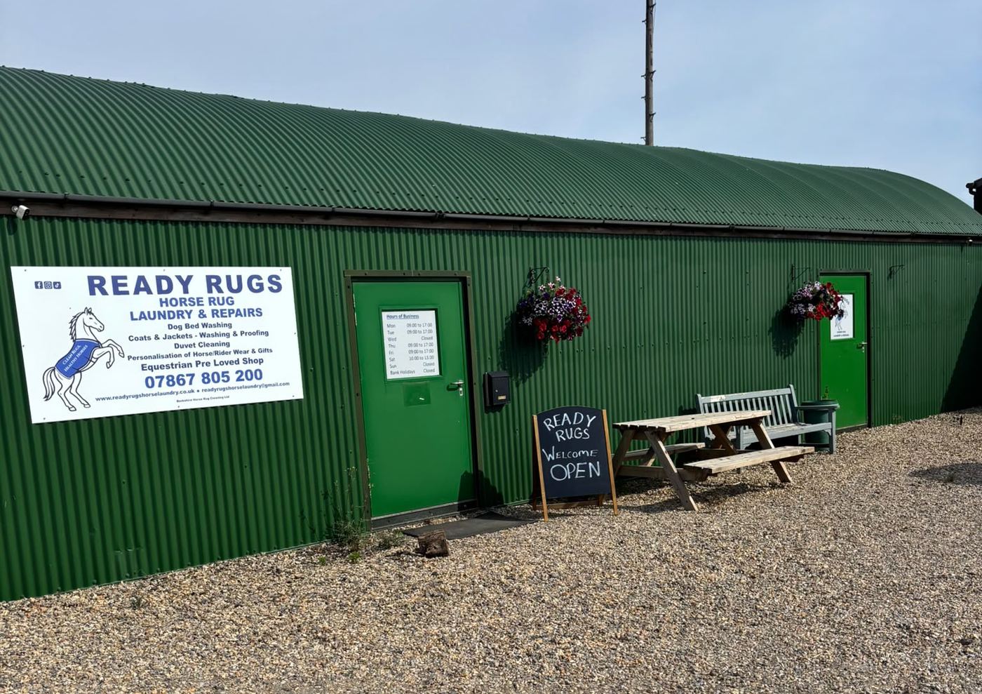 The Ready Rugs workshop at Field Barn Farm: a green barn with the Ready Rugs sign and an Open board outside