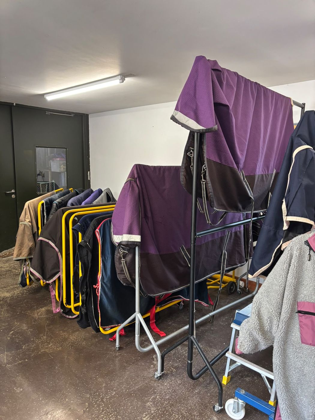 Freshly washed horse rugs drying on racks in the workshop